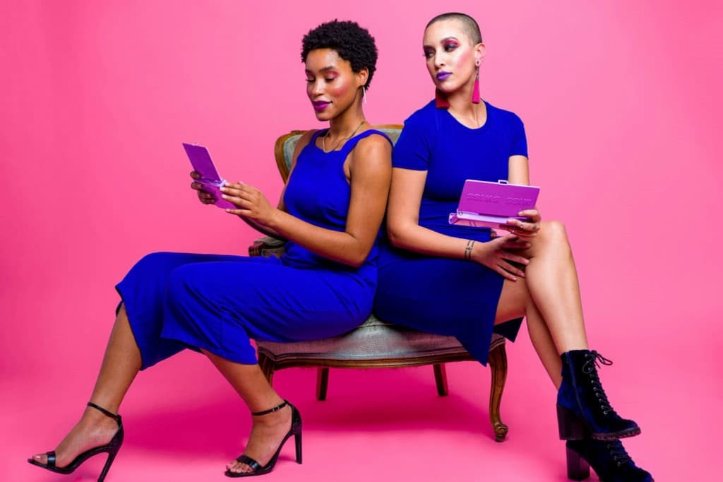 Two founders in cobalt-blue dresses photographed against a vibrant pink backdrop.